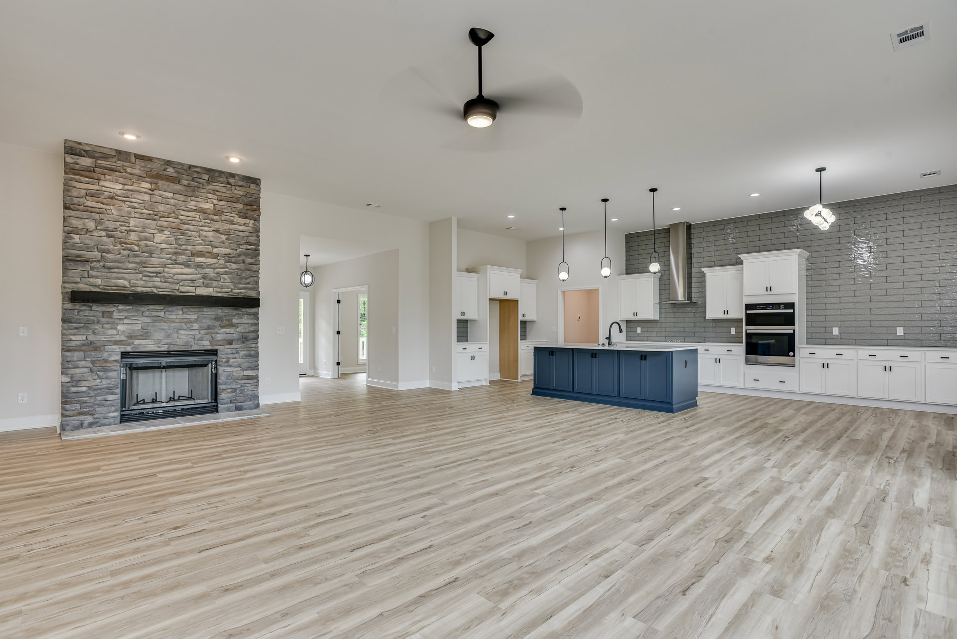 Spacious open-plan room featuring a white plaster fireplace with a screen, hardwood flooring, blue kitchen cabinets with black handles, and a central kitchen island.
