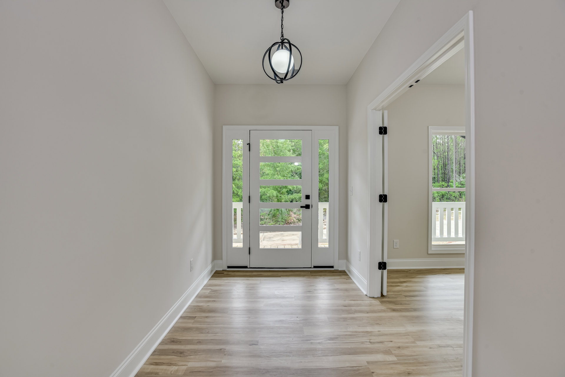 Hallway with hardwood flooring, white door featuring glass panels, and a chain-hung light fixture