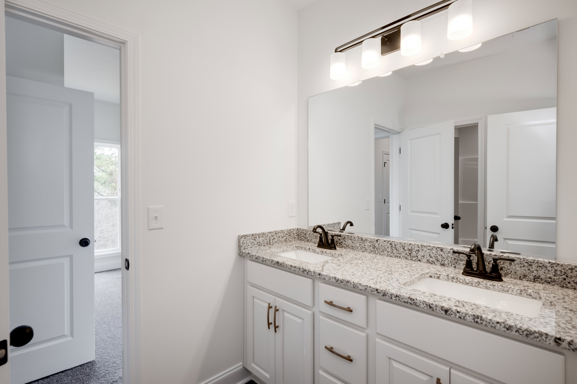 Bathroom with marble countertop, undermount sink, large framed mirror, white walls, chrome faucet, and light switch.
