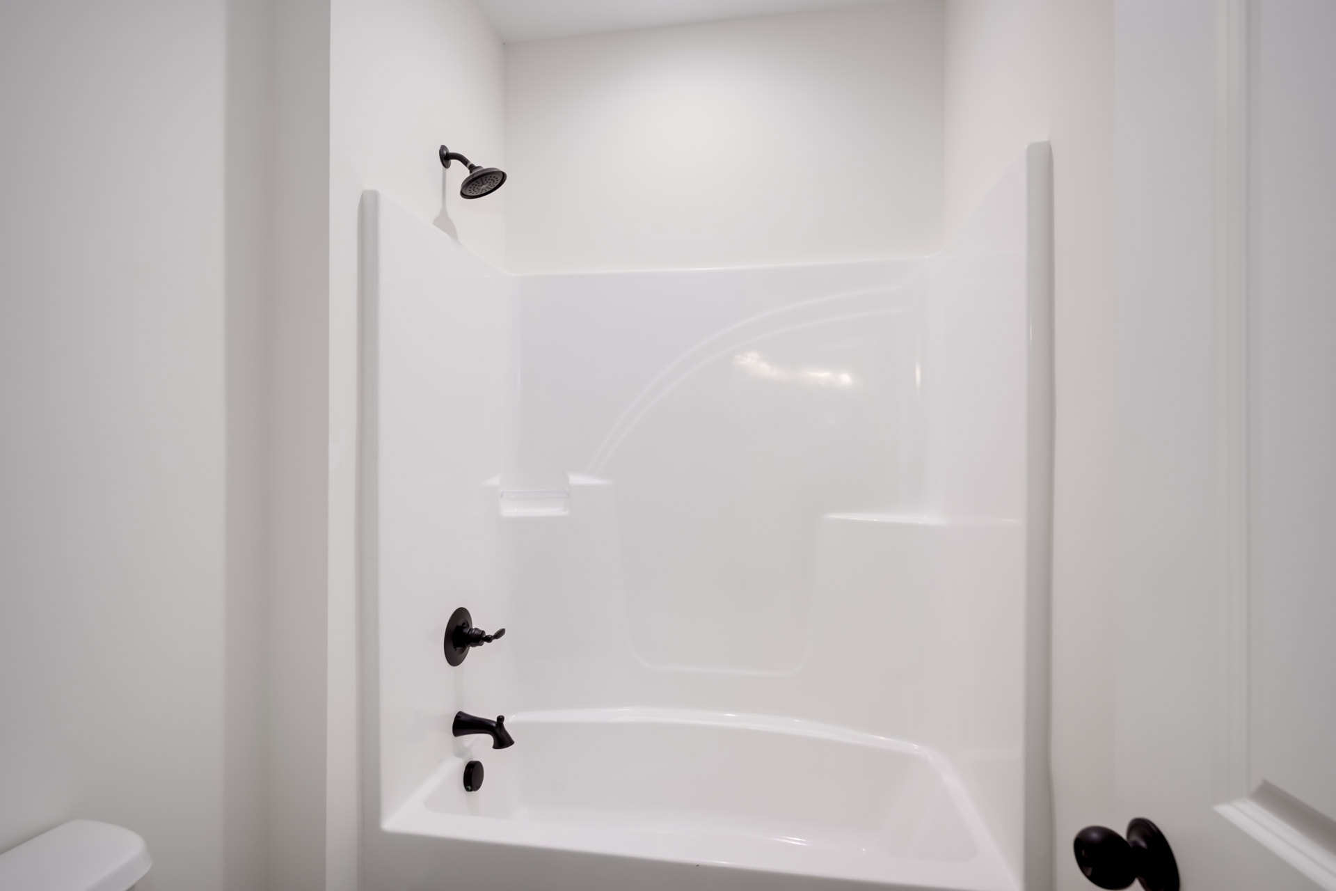 Freestanding white bathtub with matte black faucet and fixtures against a light bathroom wall