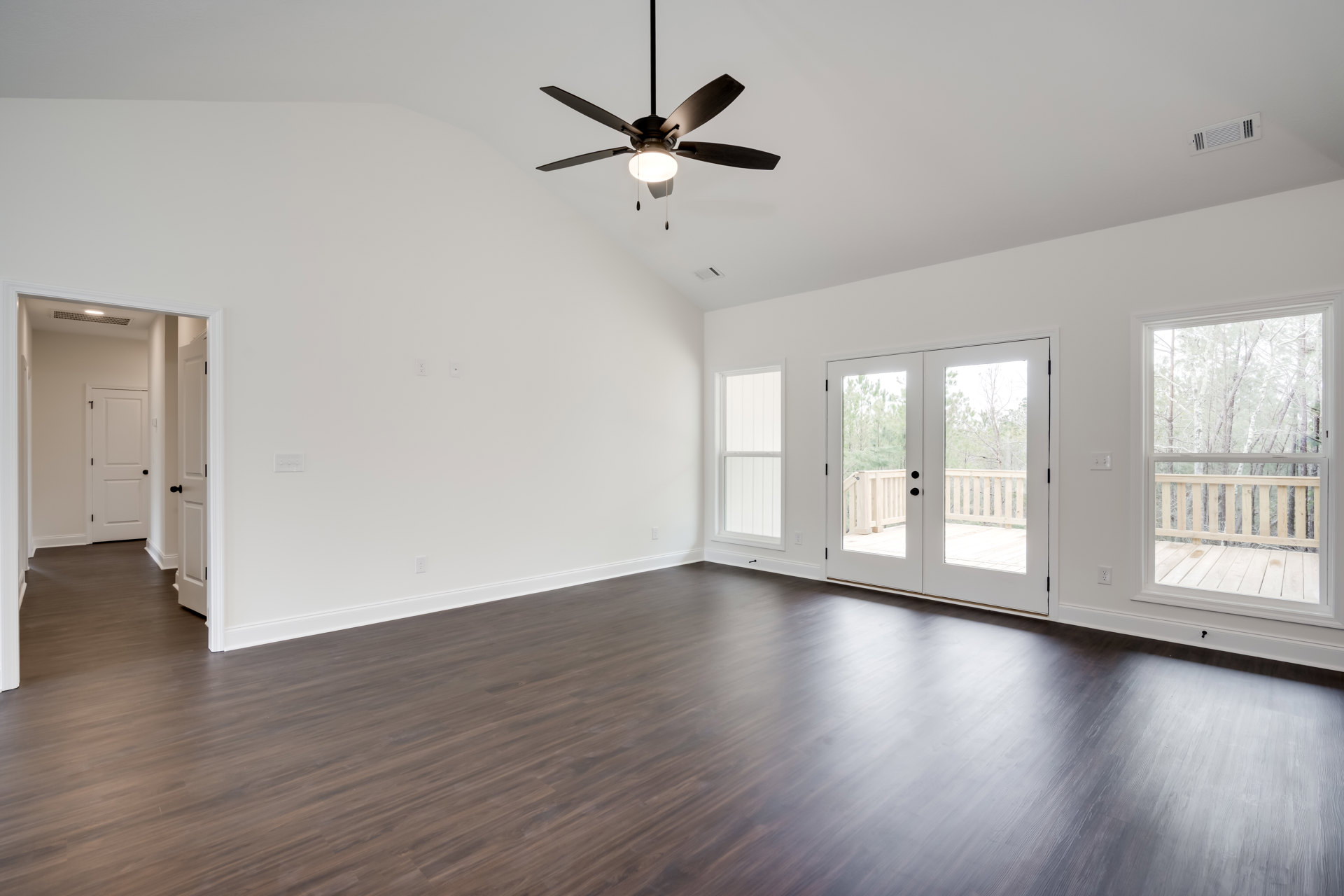 Ceiling fan with light fixture, wood flooring, white walls, window with white frame, white door with black handle, ceiling vent