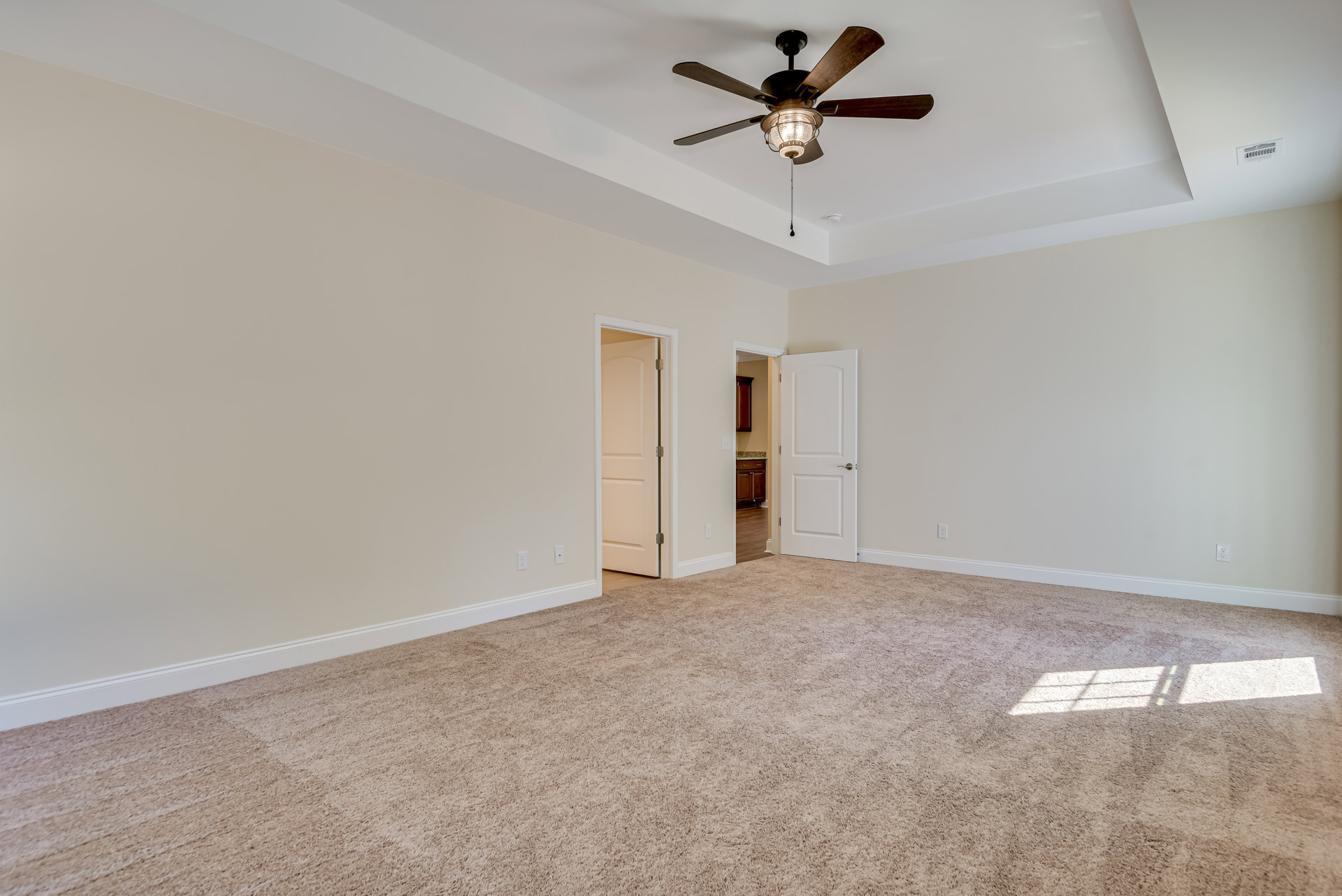 Carpeted room with white walls and trim, ceiling fan with light fixture, white door with silver handle