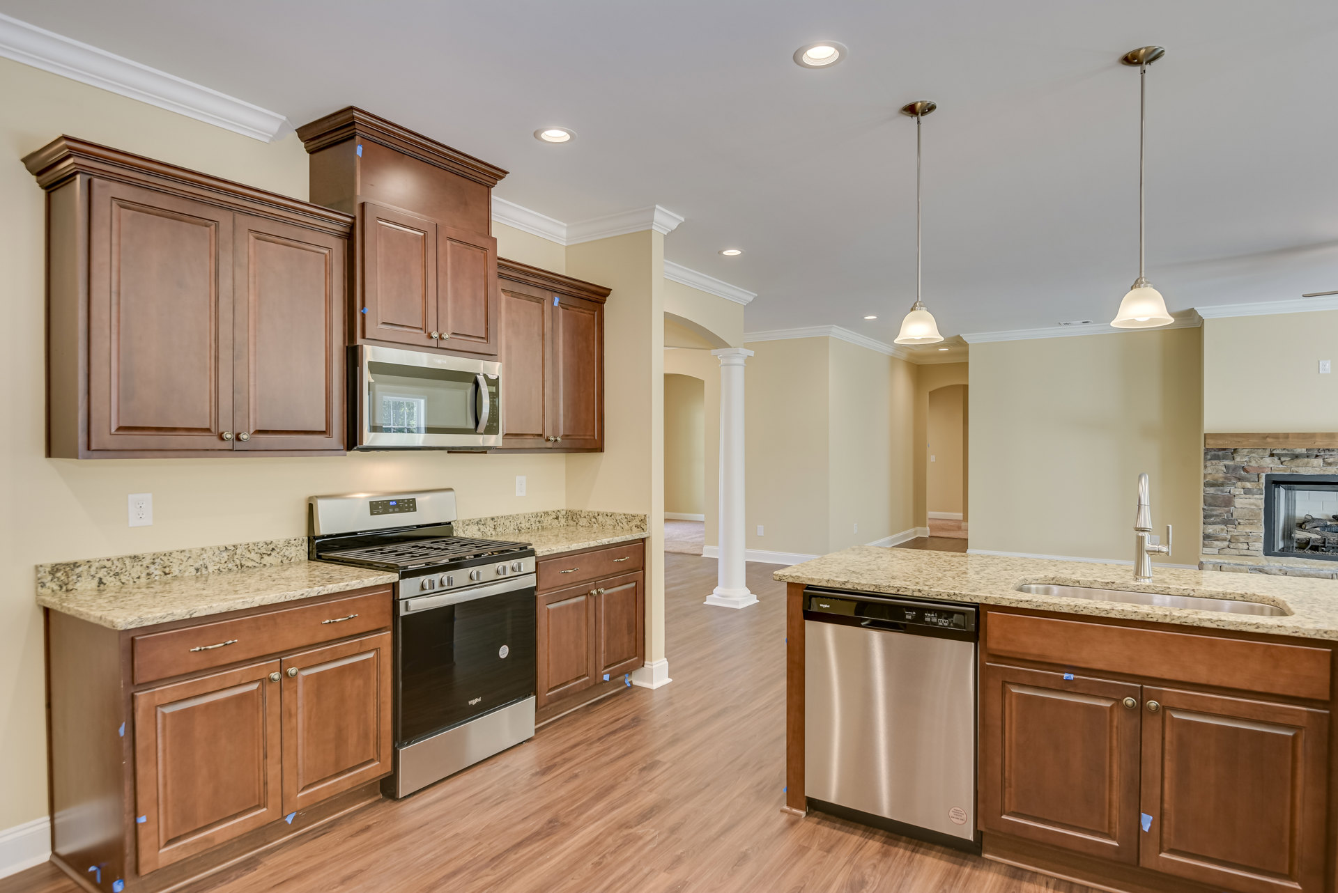 Kitchen featuring wood cabinetry, granite countertops, stainless steel stove and oven, built-in microwave, silver dishwasher, and light-colored flooring