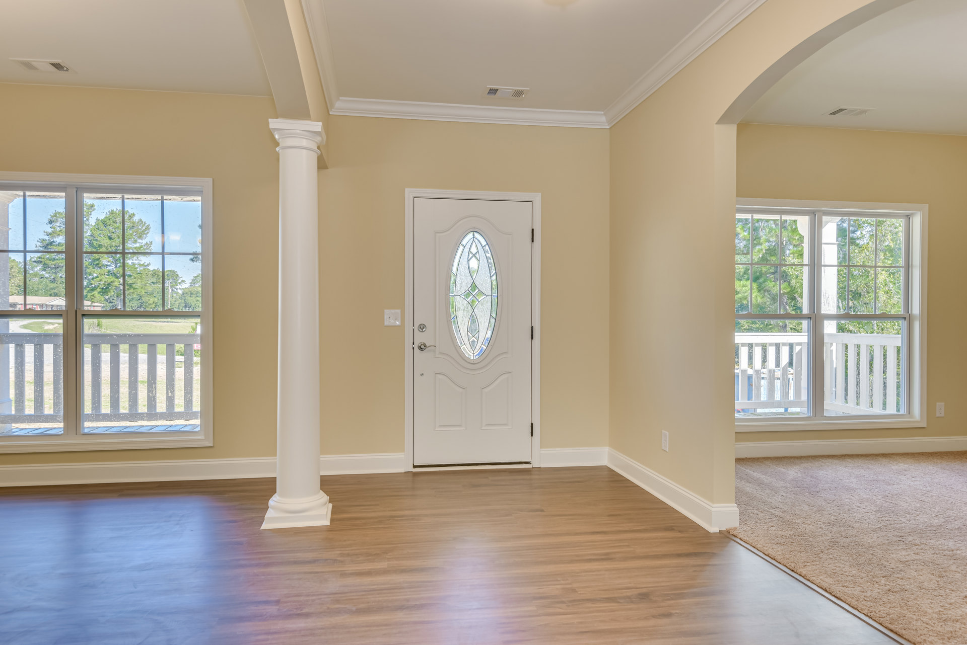 White paneled door with stained glass window, hardwood flooring, white walls, ceiling vent, and decorative molding