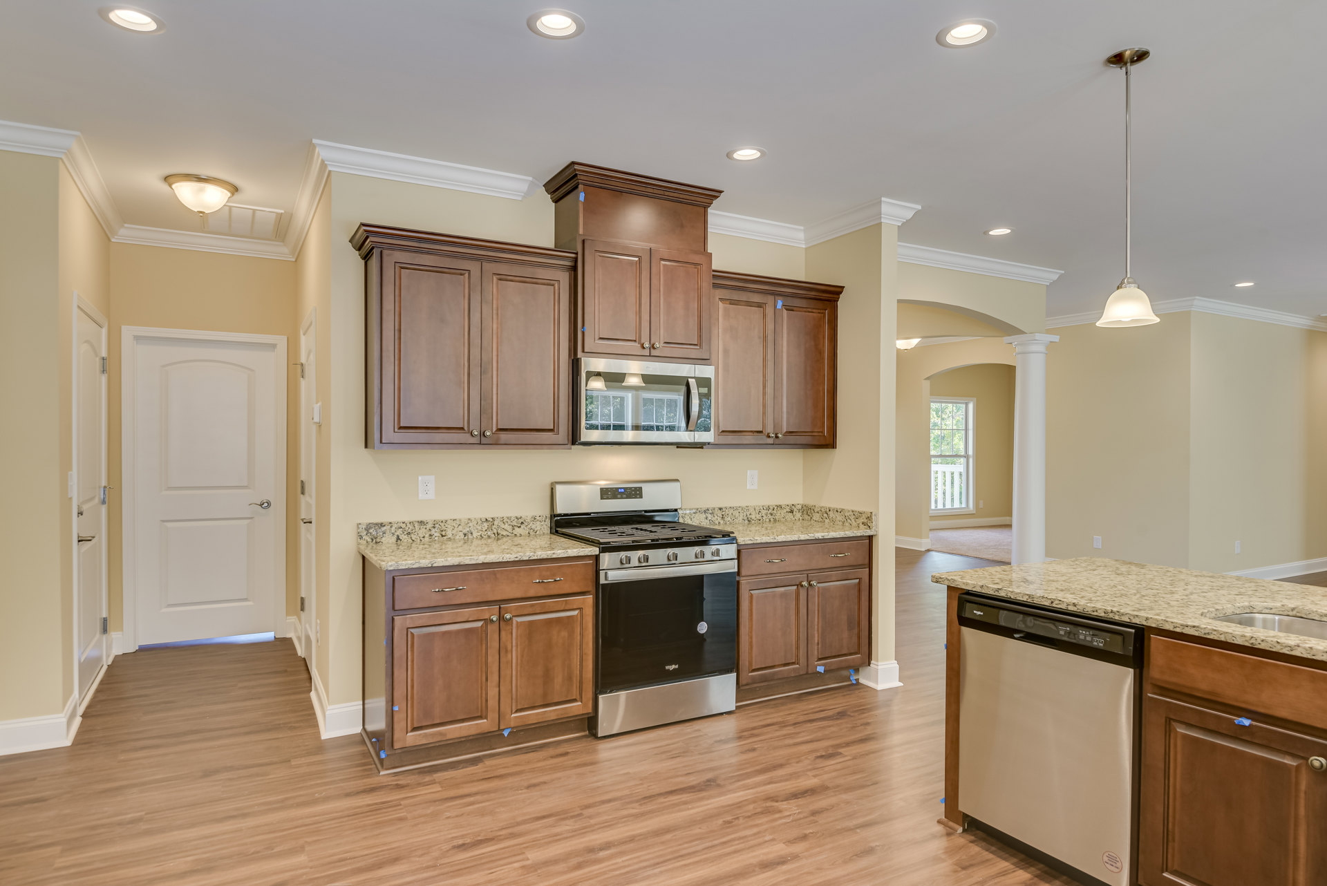 Modern kitchen featuring stainless steel stove and oven, white cabinetry with silver handles, wooden cabinets, light countertops, and tiled flooring