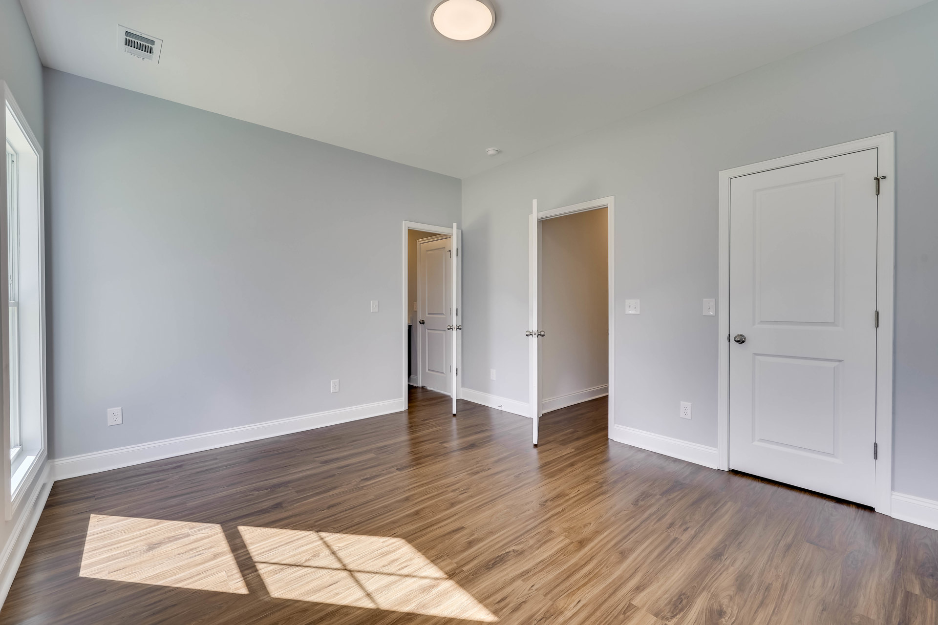 White walls and doors with silver knobs, hardwood floor, close-up of ceiling light fixture