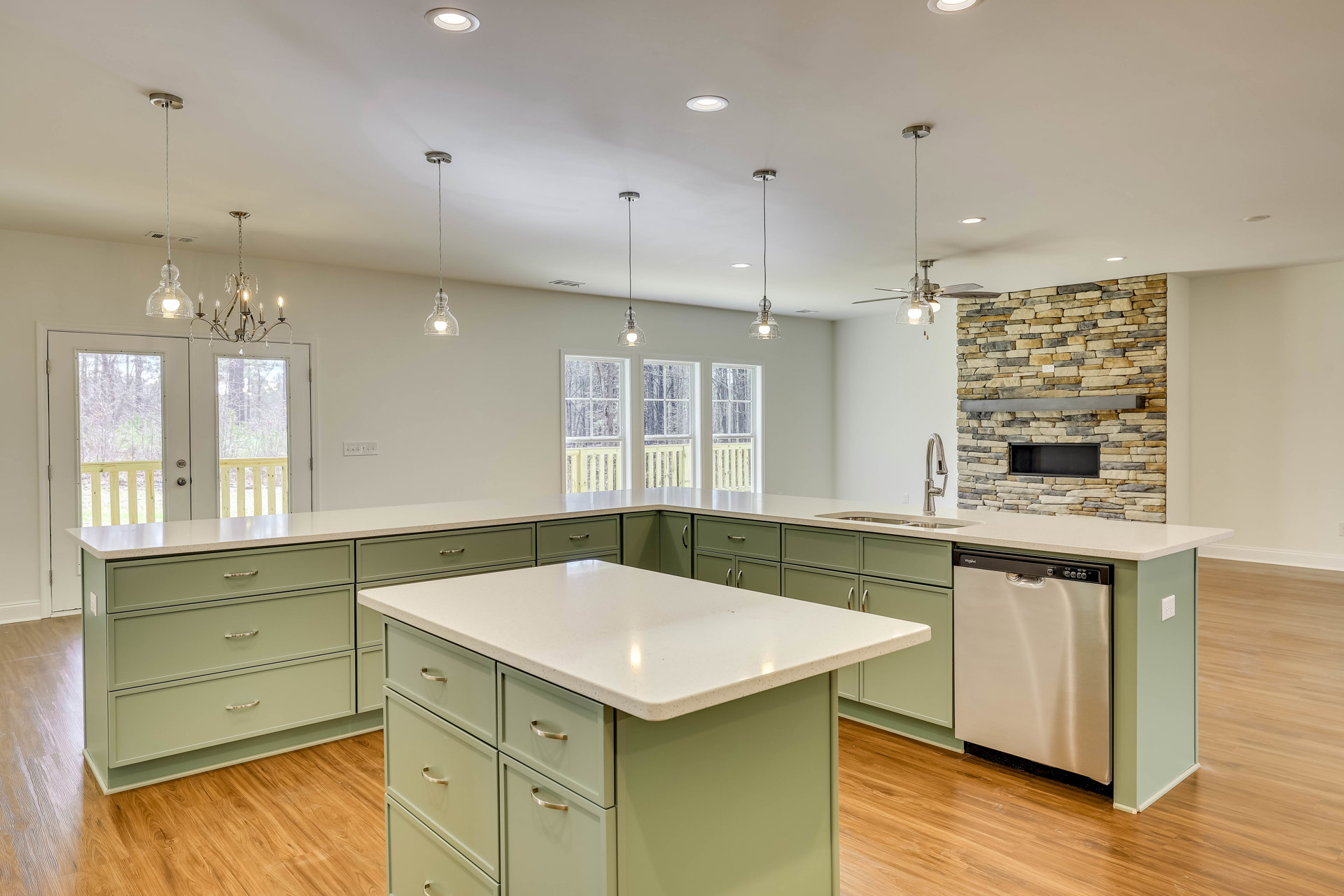 Kitchen with a large island featuring white countertop, drawers, and cabinets; stainless steel dishwasher with clip on front; tile flooring, wall cabinetry, and sink visible
