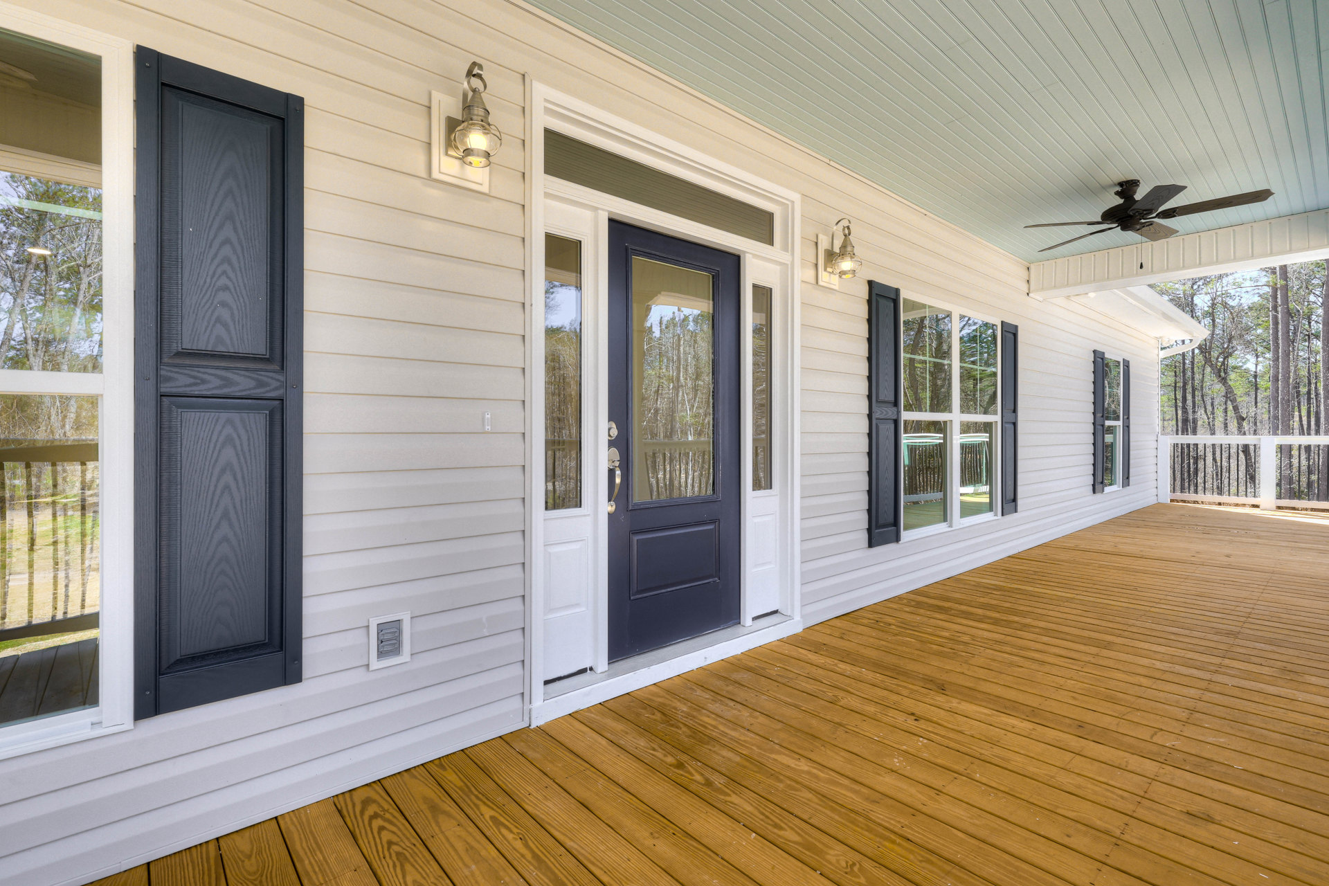 White siding home with blue front door, large windows, and wood deck porch