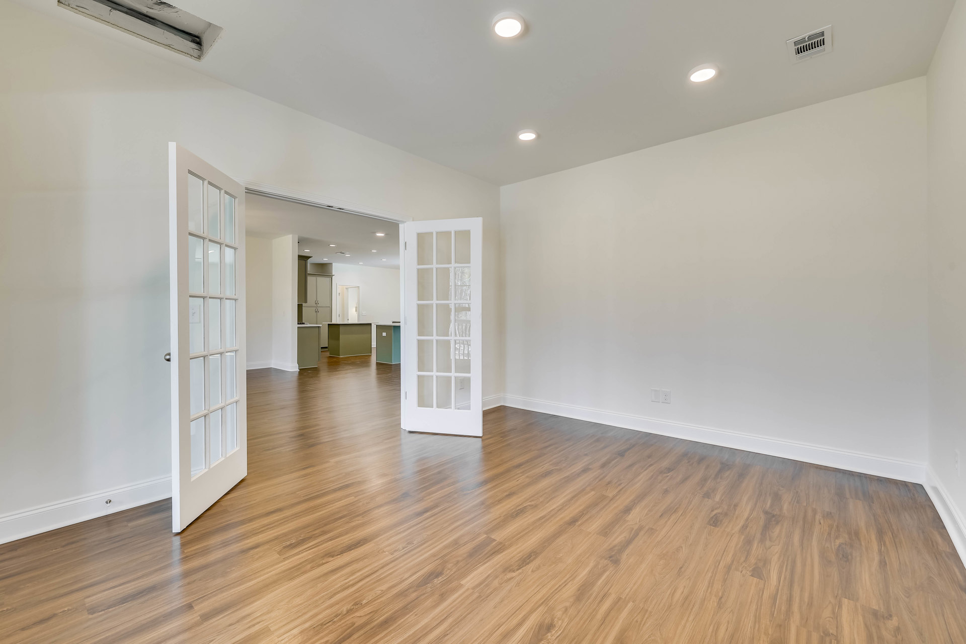 White walls, wood flooring, open white door with glass panes, ceiling light fixture