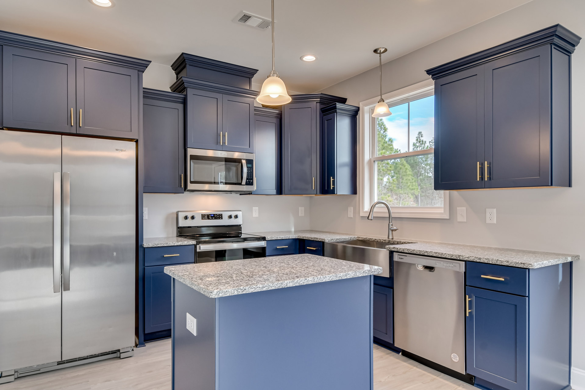 Blue shaker cabinets, stainless steel French door refrigerator, open microwave, quartz countertop, gas stove, pendant lamp, white tile backsplash