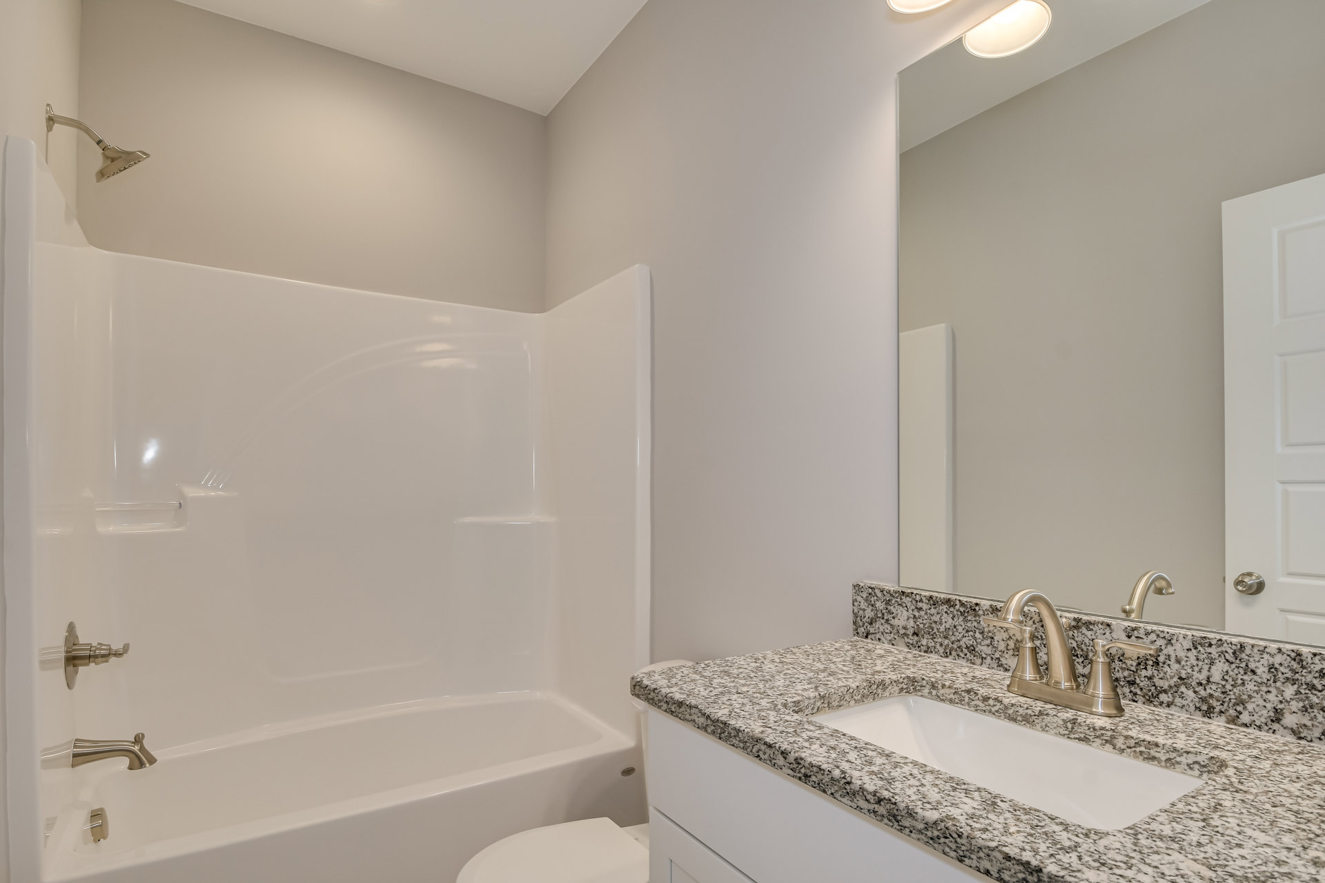 Modern bathroom featuring a white porcelain sink with chrome faucet, glass-enclosed shower with tile walls, and a freestanding white bathtub adjacent to a paneled door.