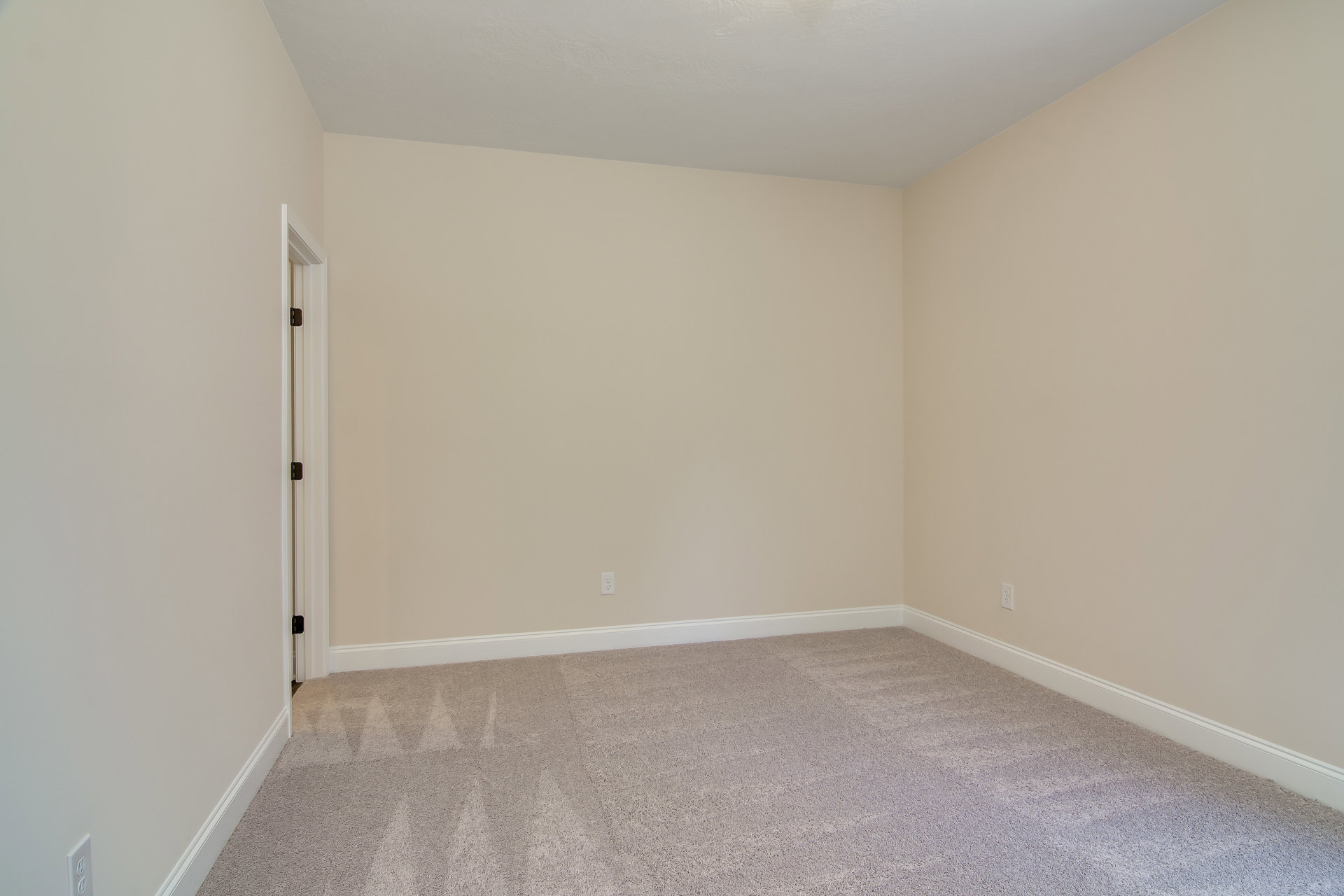 White carpeted floor, white walls and ceiling, white door with matte black hinges