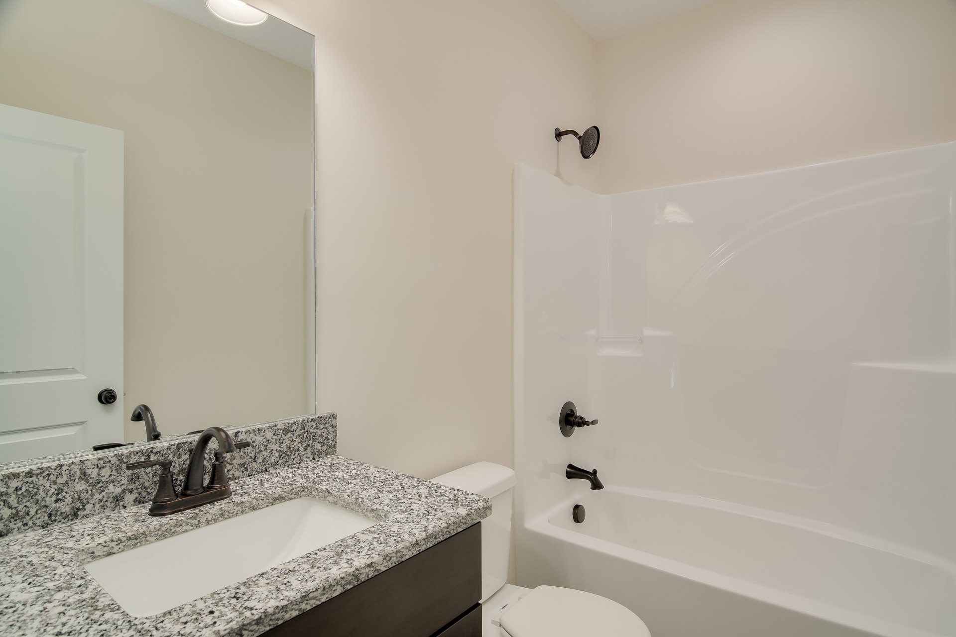 Bathroom with marble countertop sink, wall-mounted faucet, white bathtub, toilet, tiled walls, and glass shower enclosure