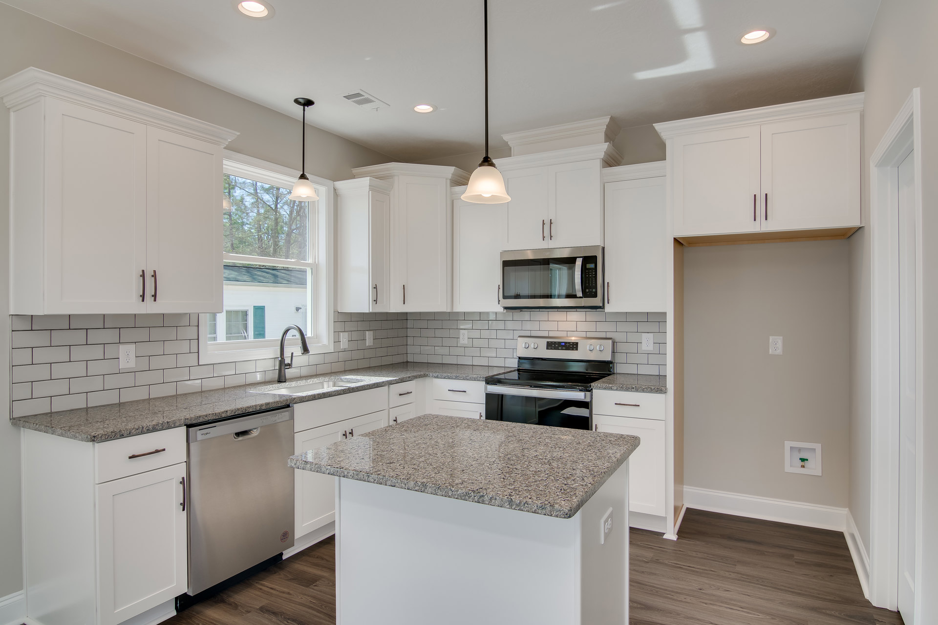 White kitchen with shaker cabinets, granite island, stainless steel refrigerator, built-in microwave, glass-door stove, and light tile flooring