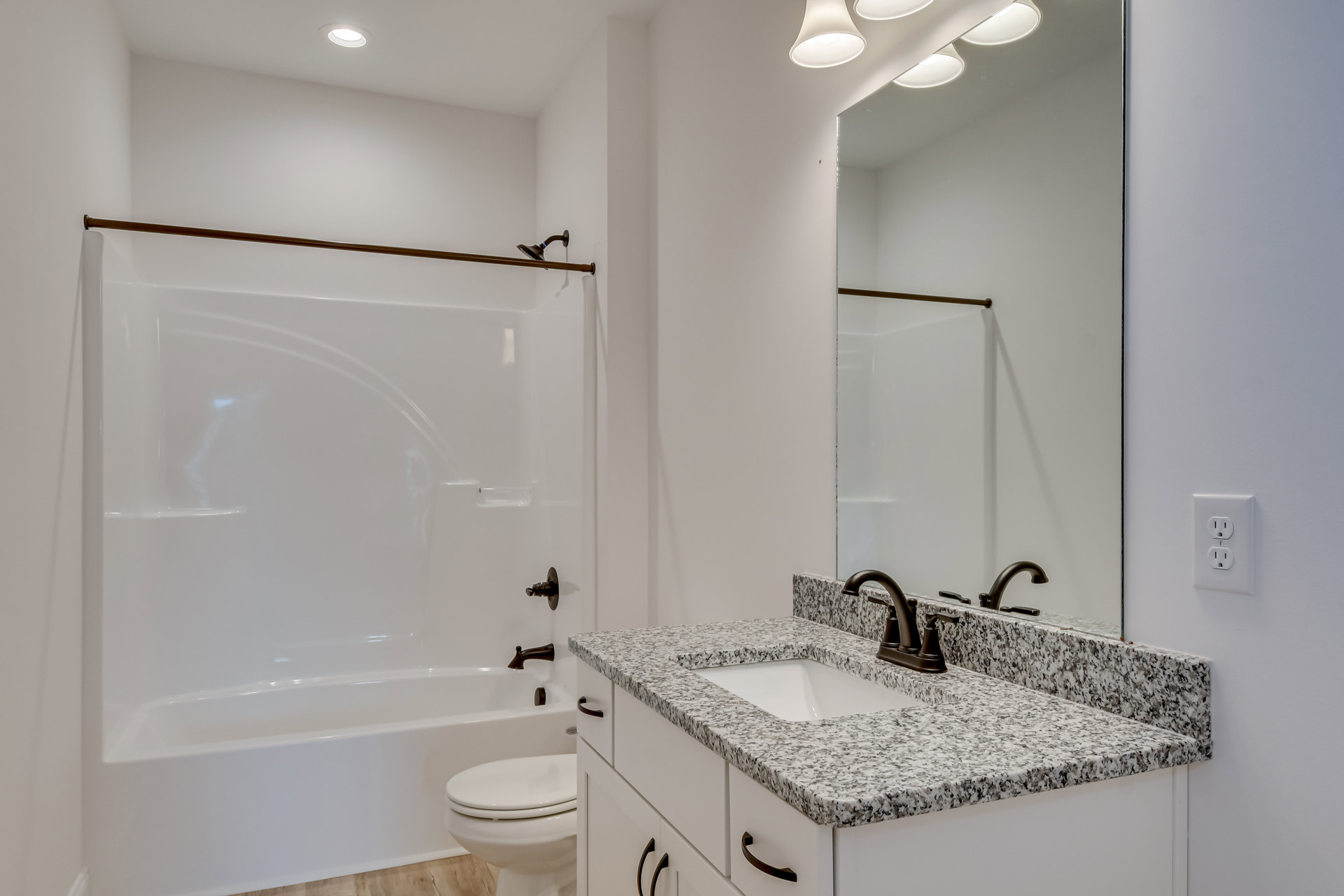 Modern bathroom with white tile walls, glass-enclosed shower, rectangular sink with chrome faucet, large frameless mirror, white bathtub, and toilet.