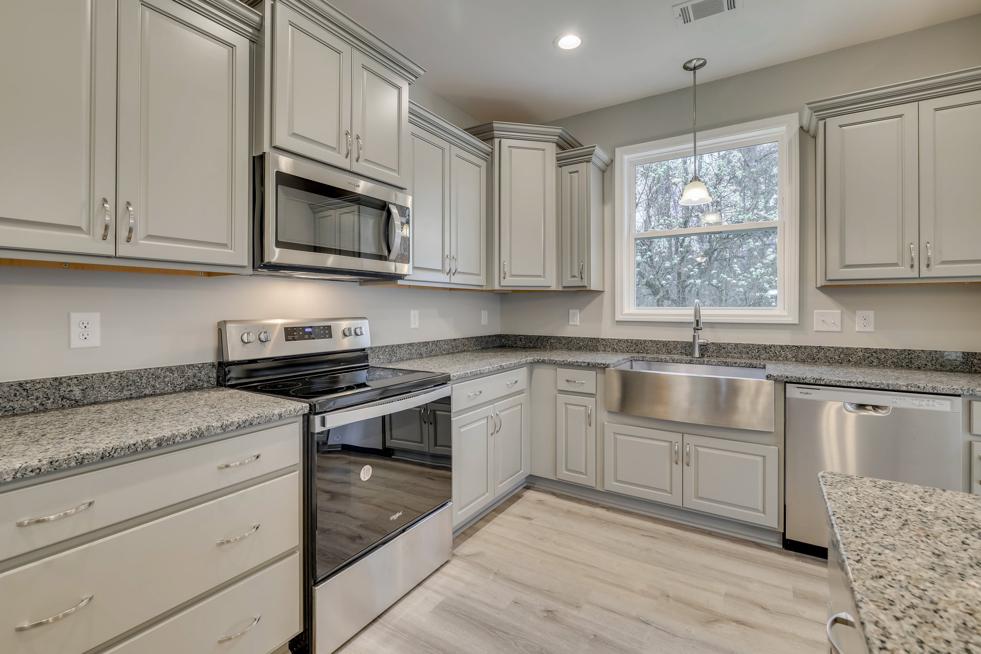 Granite countertops with stainless steel sink, white cabinetry, built-in microwave, stove and oven, window above sink, modern light fixture