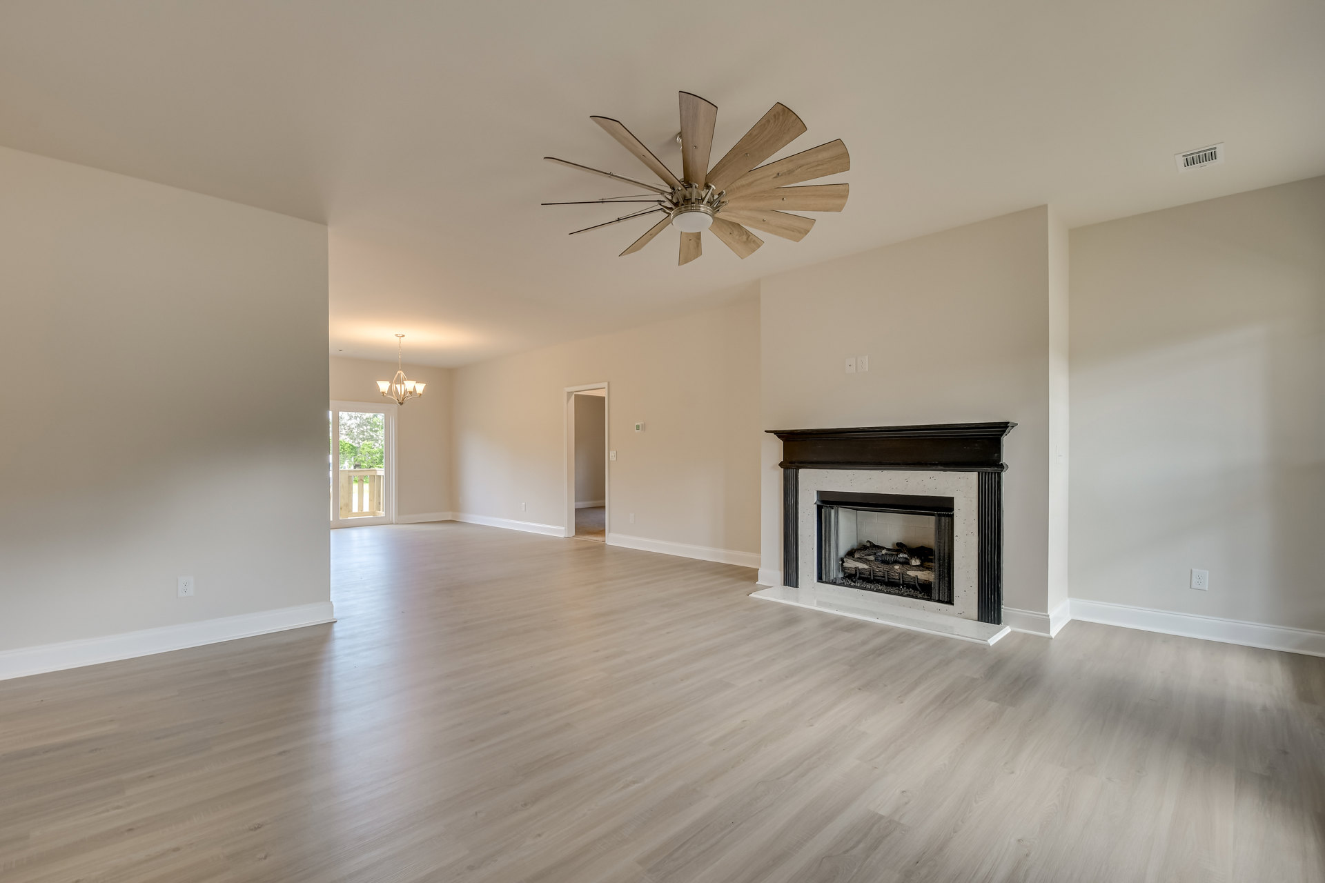 Living room with hardwood floors, white plaster walls, black-framed fireplace, ceiling fan with light fixture, crown molding, and wood trim