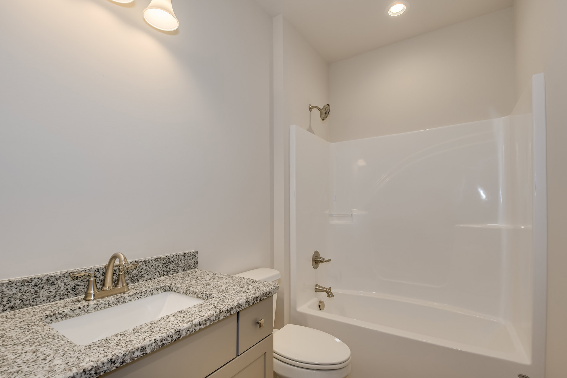 Modern bathroom with white porcelain sink, silver faucet, white toilet, tiled walls, and bathtub visible in the background