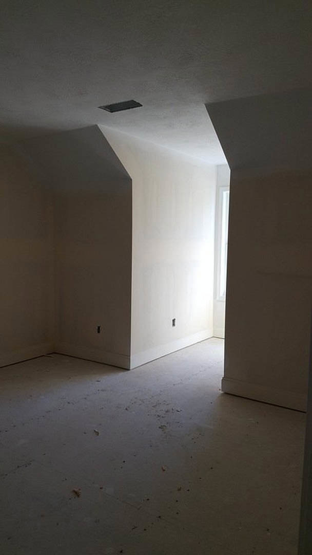 White-walled room with large window, light streaming onto smooth plaster walls and hardwood flooring, ceiling vent visible above