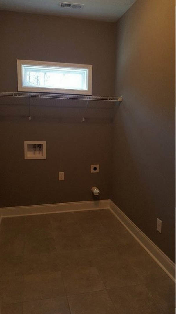Bathroom with white plaster walls, built-in shelves beside a rectangular window, tile flooring, and a baseboard heater.