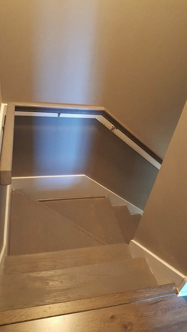 Wood staircase with aluminum railing, illuminated by wall-mounted light, featuring close-up views of wood panels and white surfaces.