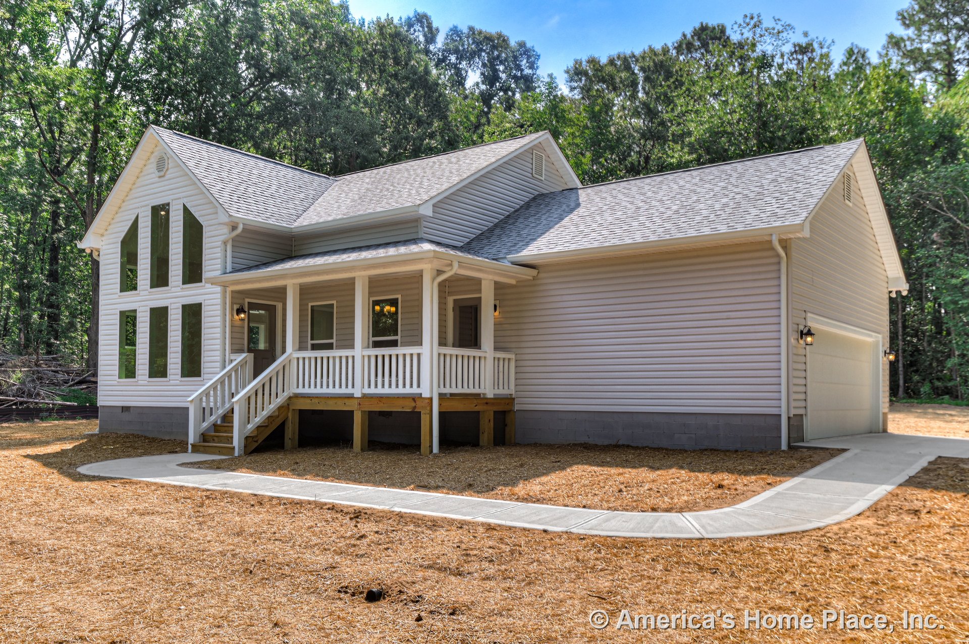 Covered front porch with stairs and railing, large vertical accent windows, attached two-car garage, vinyl siding exterior, gable roof, concrete walkway leading to entry door
