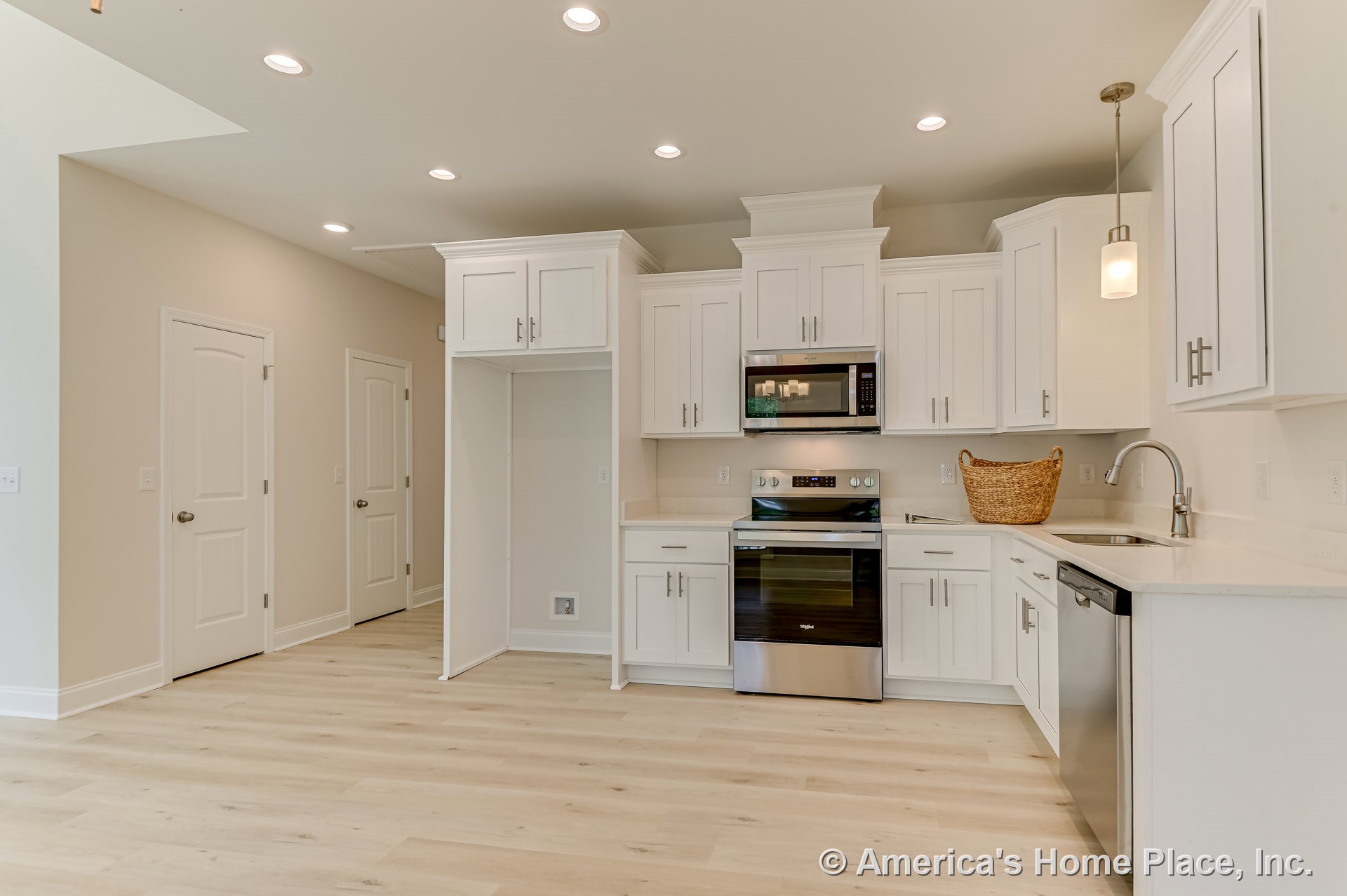 White shaker cabinets and quartz countertops with stainless steel appliances, recessed ceiling lights, pendant fixture above island, built-in microwave and oven, under-counter