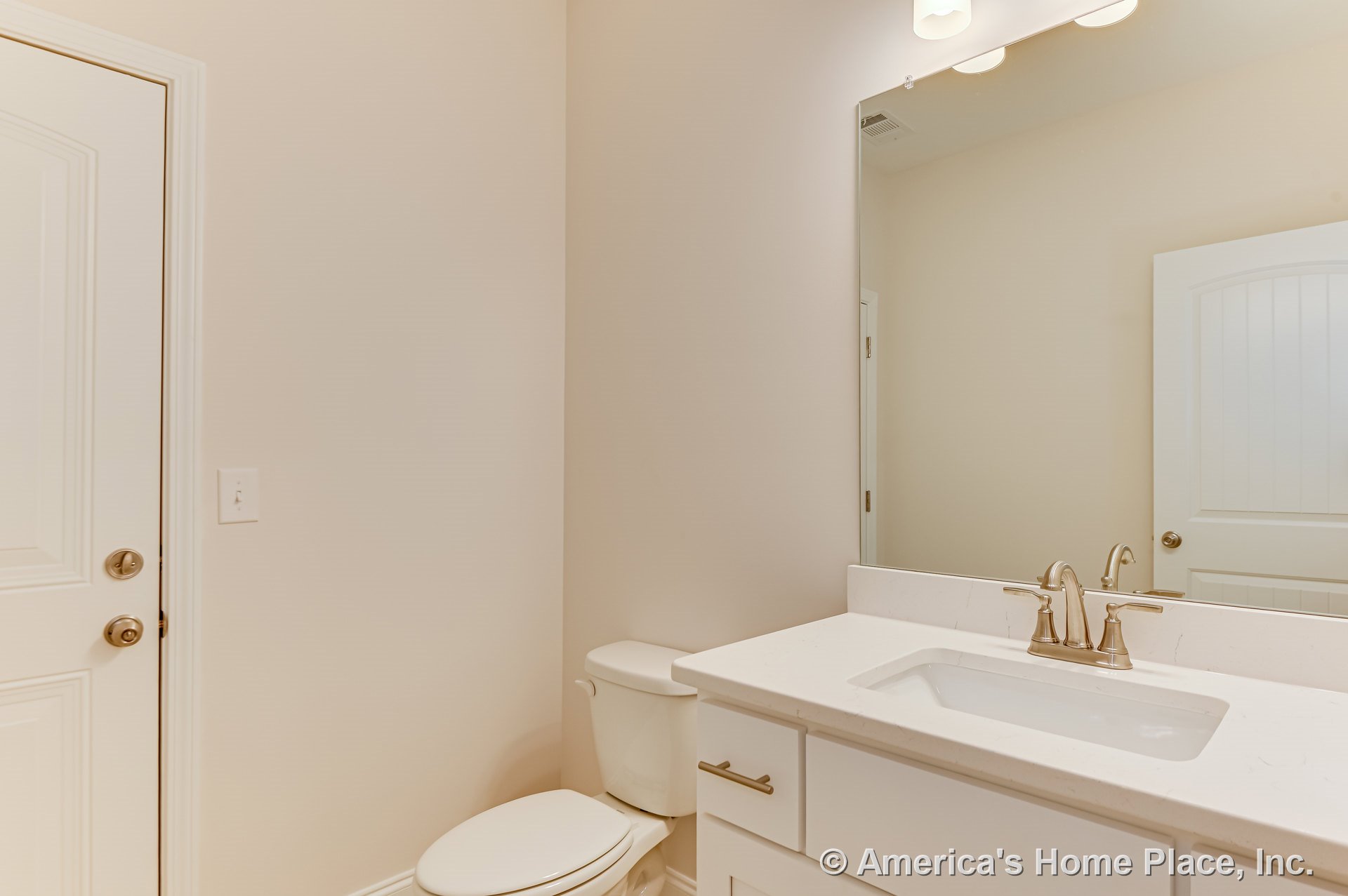 White shaker vanity with quartz countertop and brushed nickel faucet, large wall mirror above, recessed lighting, paneled interior door, neutral walls, and built-in toilet.