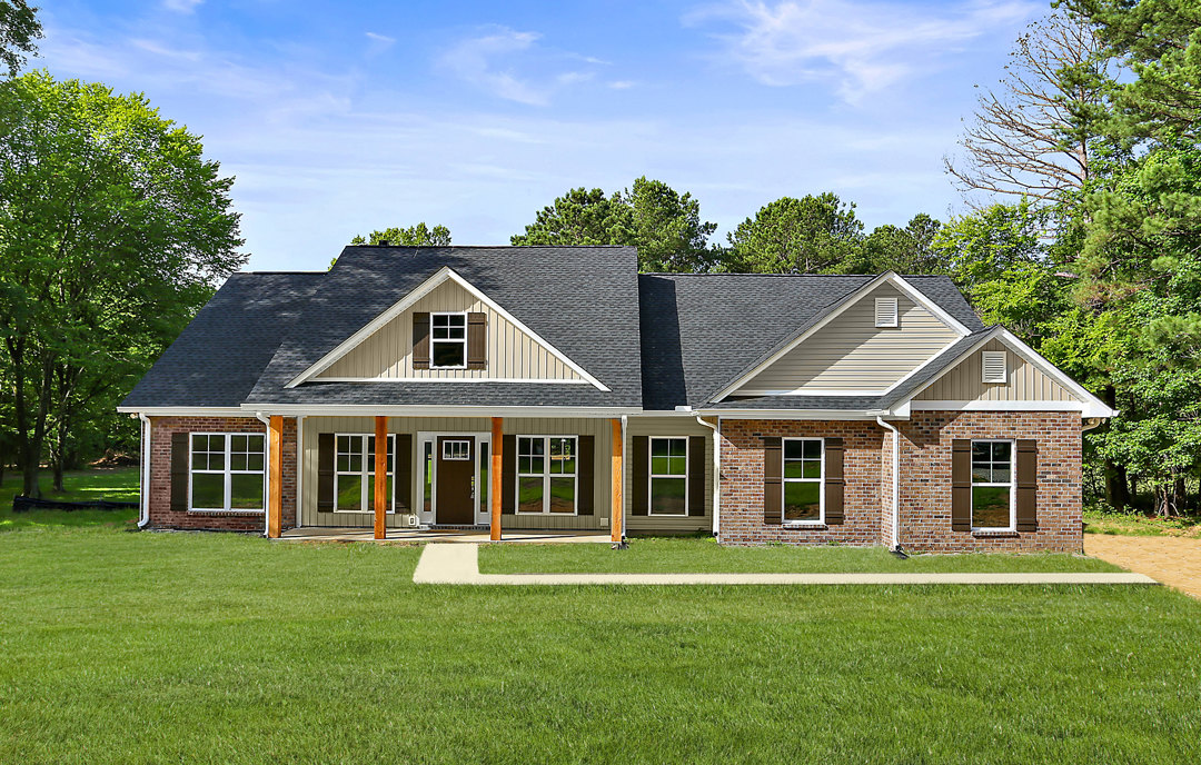 Brick house with white-framed windows, gabled roof, green lawn, and mature trees in the background
