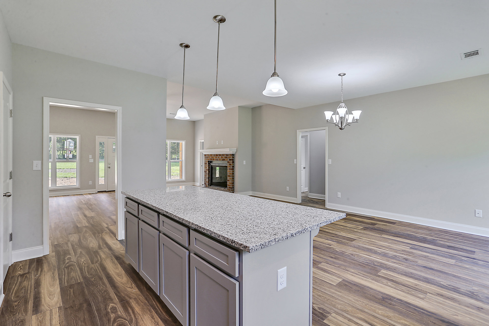 Granite kitchen island with built-in sink, white cabinetry, tile flooring, and pendant lighting in a modern residential interior