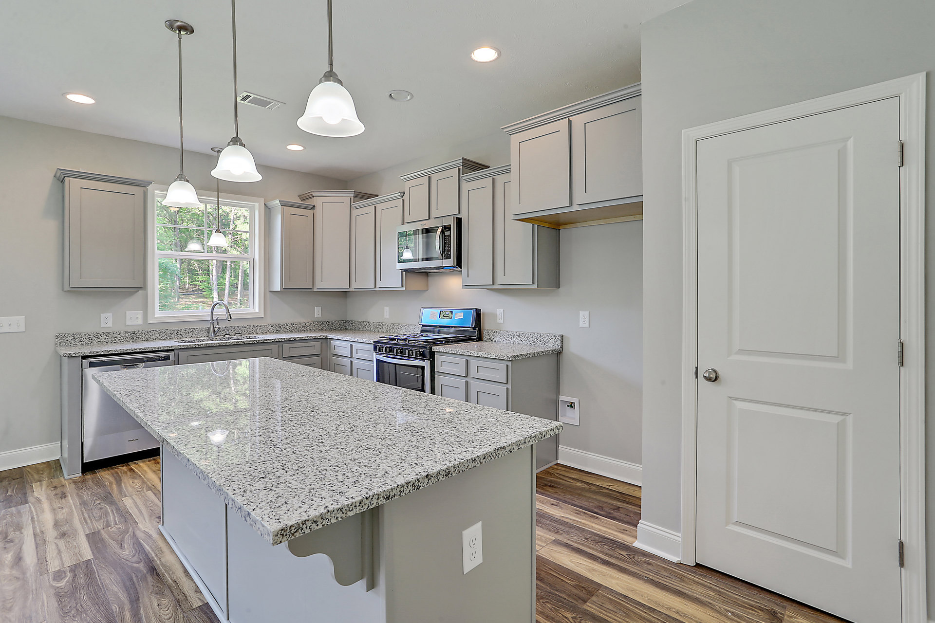 Kitchen with granite countertops, wood flooring, white cabinetry, stainless steel appliances, and a microwave above the stove.