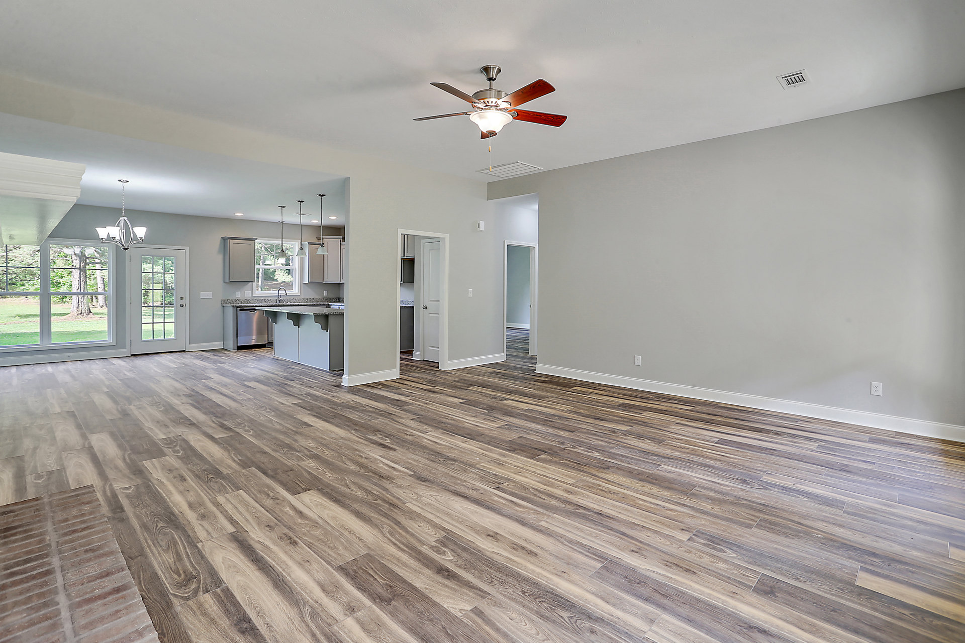 Wood flooring and white walls, ceiling fan with light fixture, glass-paneled door, white door with black sign, close-up of wood trim