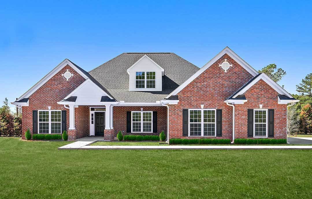 Red brick house with white roof, black shuttered windows, multi-pane glass, and green lawn; Fort Washington visible in the distant background