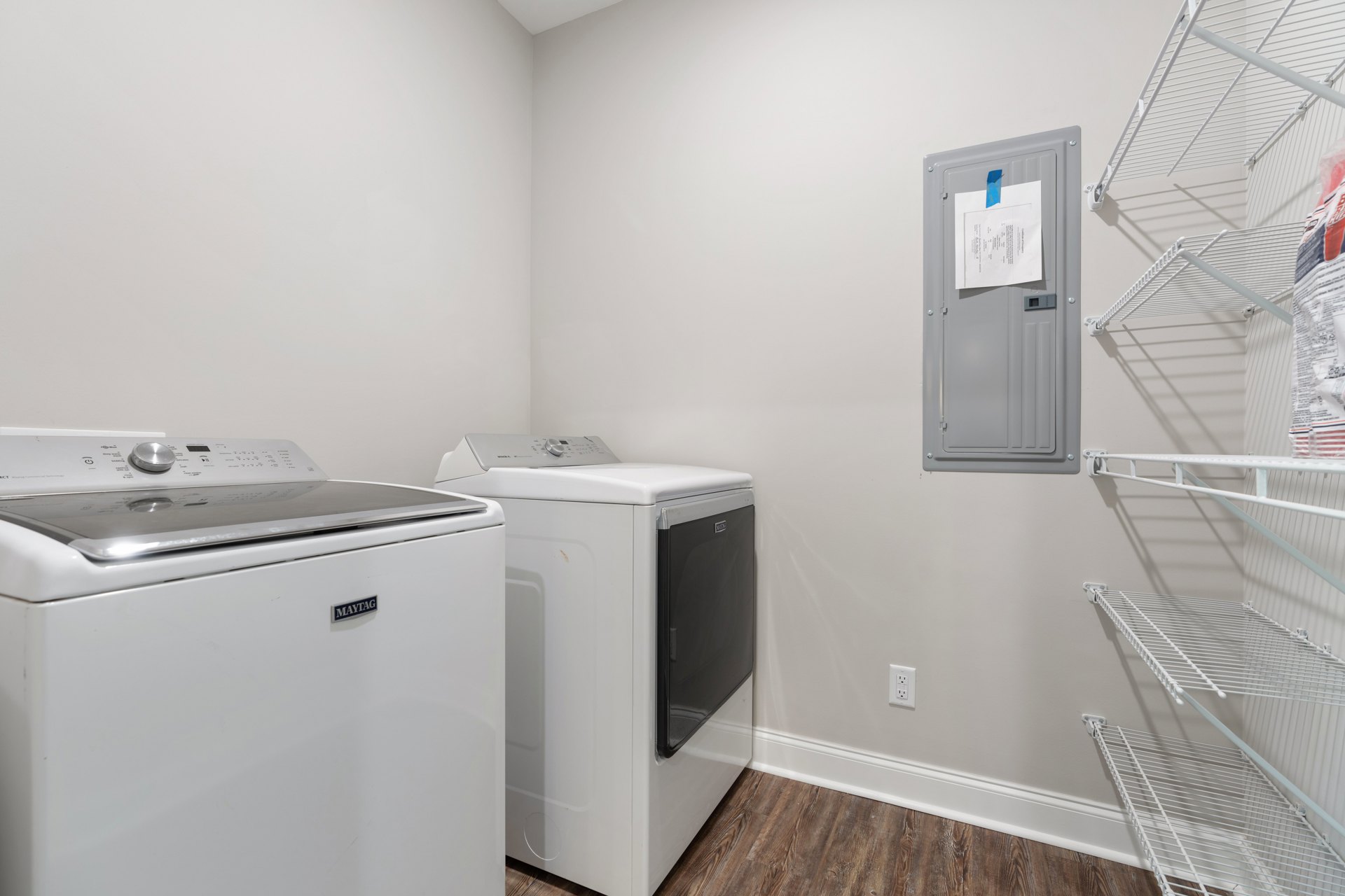 Front-loading washer and dryer set in a laundry room with white cabinetry, light-colored countertops, and tile flooring