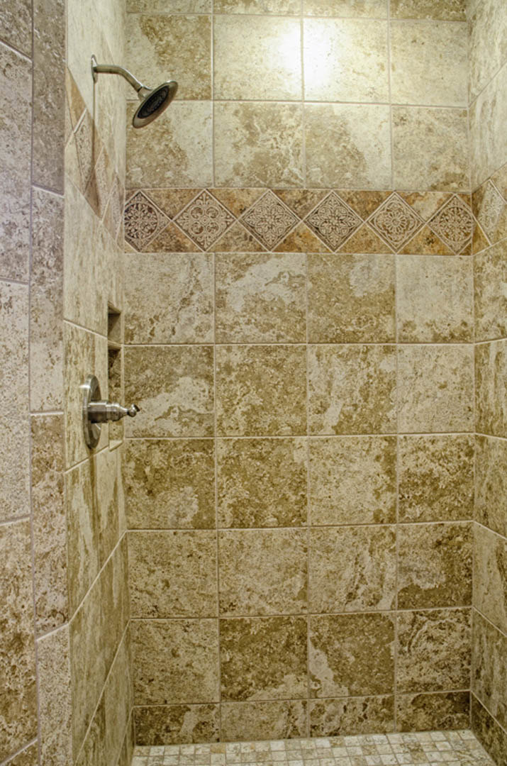 Shower with marble tile walls, black round showerhead, and tile flooring in a modern bathroom