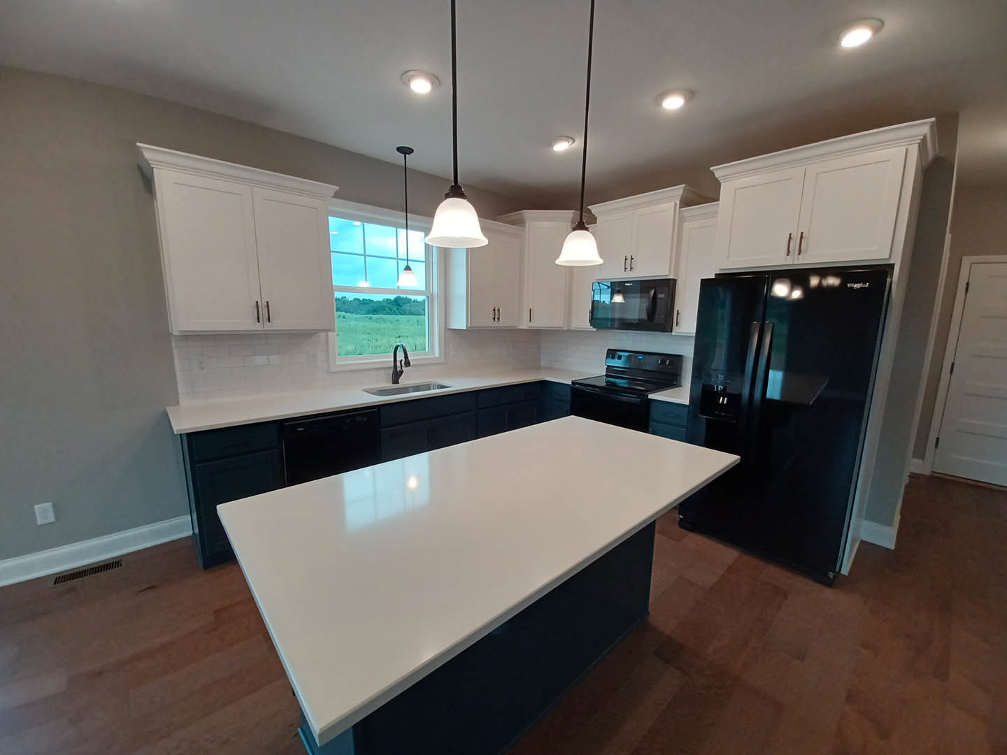 White kitchen cabinets, black refrigerator, white countertop, black stove with blue light, ceiling light fixture, neutral flooring