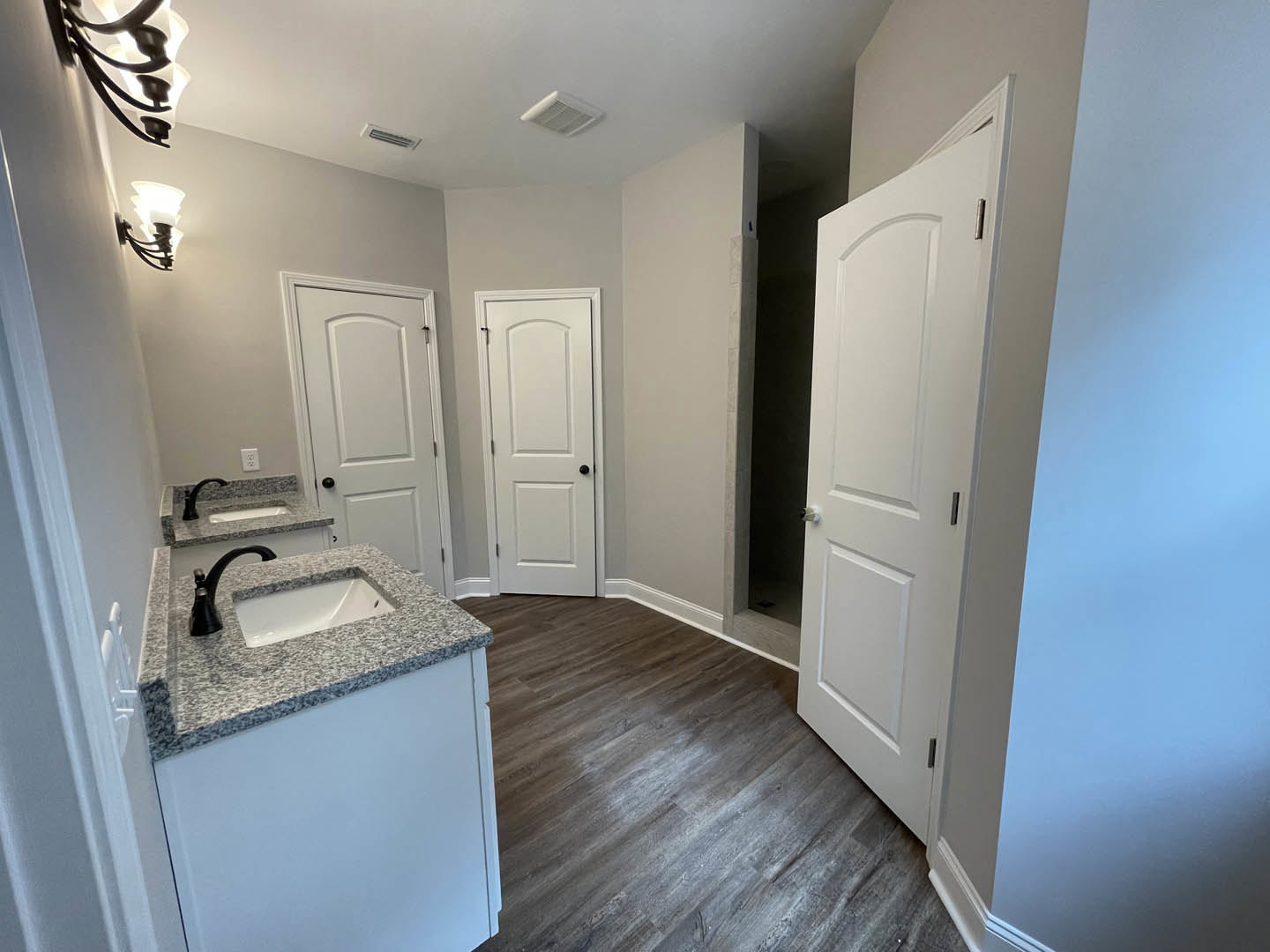 Bathroom with white paneled doors, marble countertop vanity, undermount sink with black faucet, white cabinetry, and tile flooring