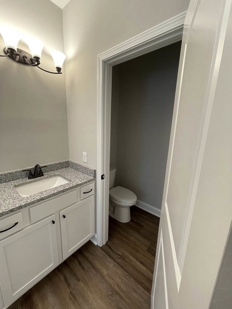 Modern bathroom featuring a white porcelain sink with chrome faucet, matching white toilet, light gray tile flooring, and neutral wall tiles