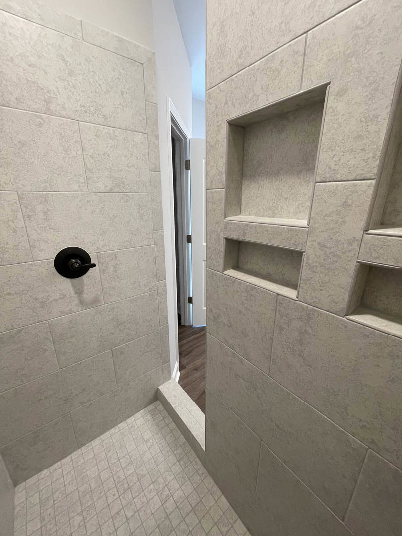 Bathroom featuring marble tile walls, large mirror above vanity, plaster finishes, and wood flooring visible near doorway.