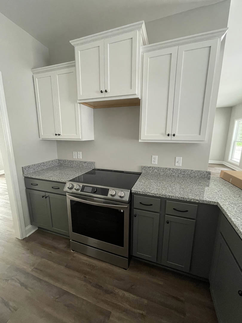 White shaker cabinets, stainless steel stove, quartz countertops, light wood flooring, subway tile backsplash