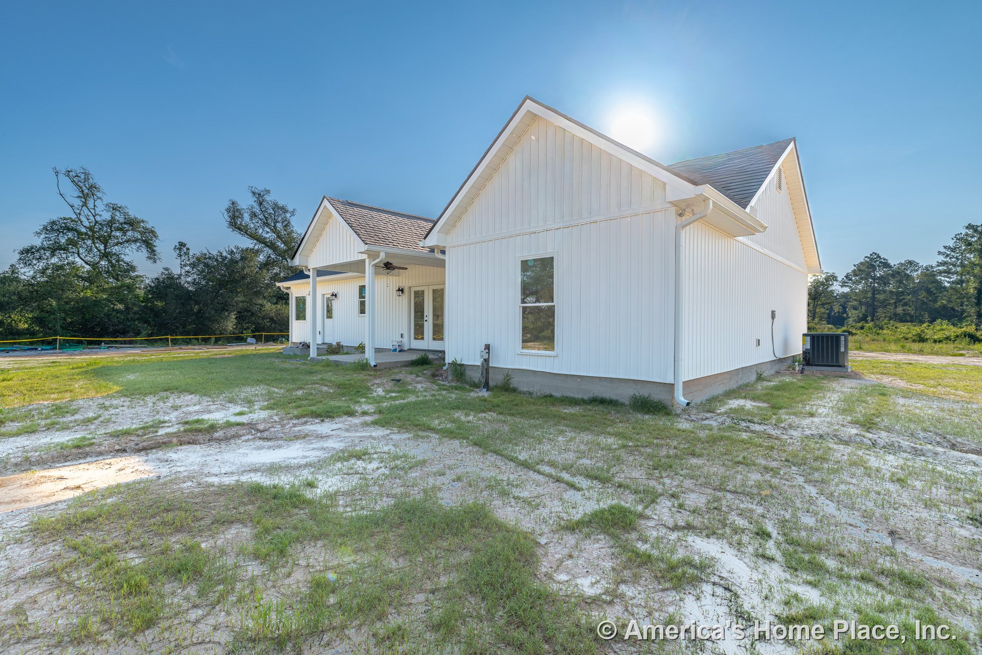 White vertical siding exterior with gabled roof, covered front porch featuring ceiling fans, multiple windows, concrete foundation, front door, outdoor lighting, downspouts, air