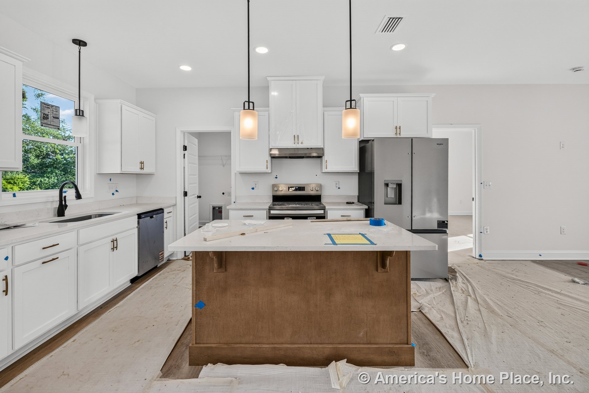 White cabinetry with quartz countertops, wood-tone central island, stainless steel refrigerator and range, pendant and recessed lighting, single-handle black faucet, tile