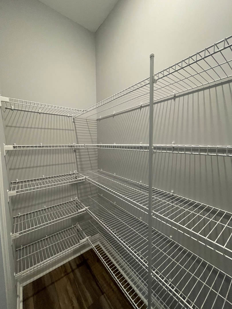 White wire shelves mounted on a wall in a room with metal mesh detailing