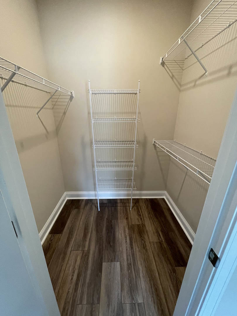 Closet with white wire shelving mounted on walls, wood flooring, and white baseboard trim