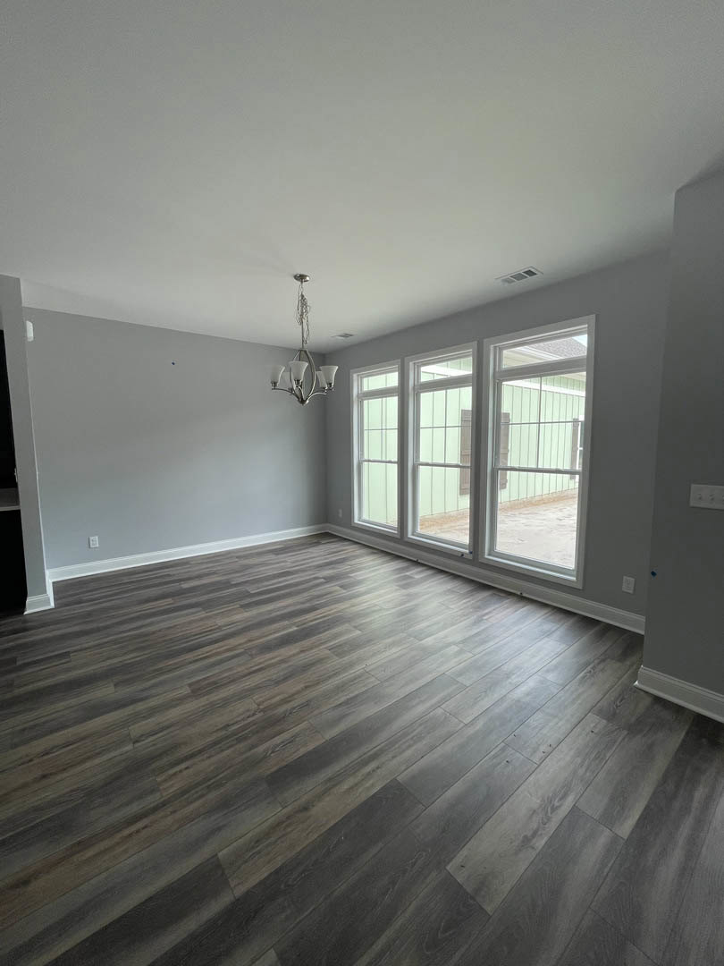 Wood floor room with white-framed windows, grey plaster walls, and a ceiling-mounted chandelier