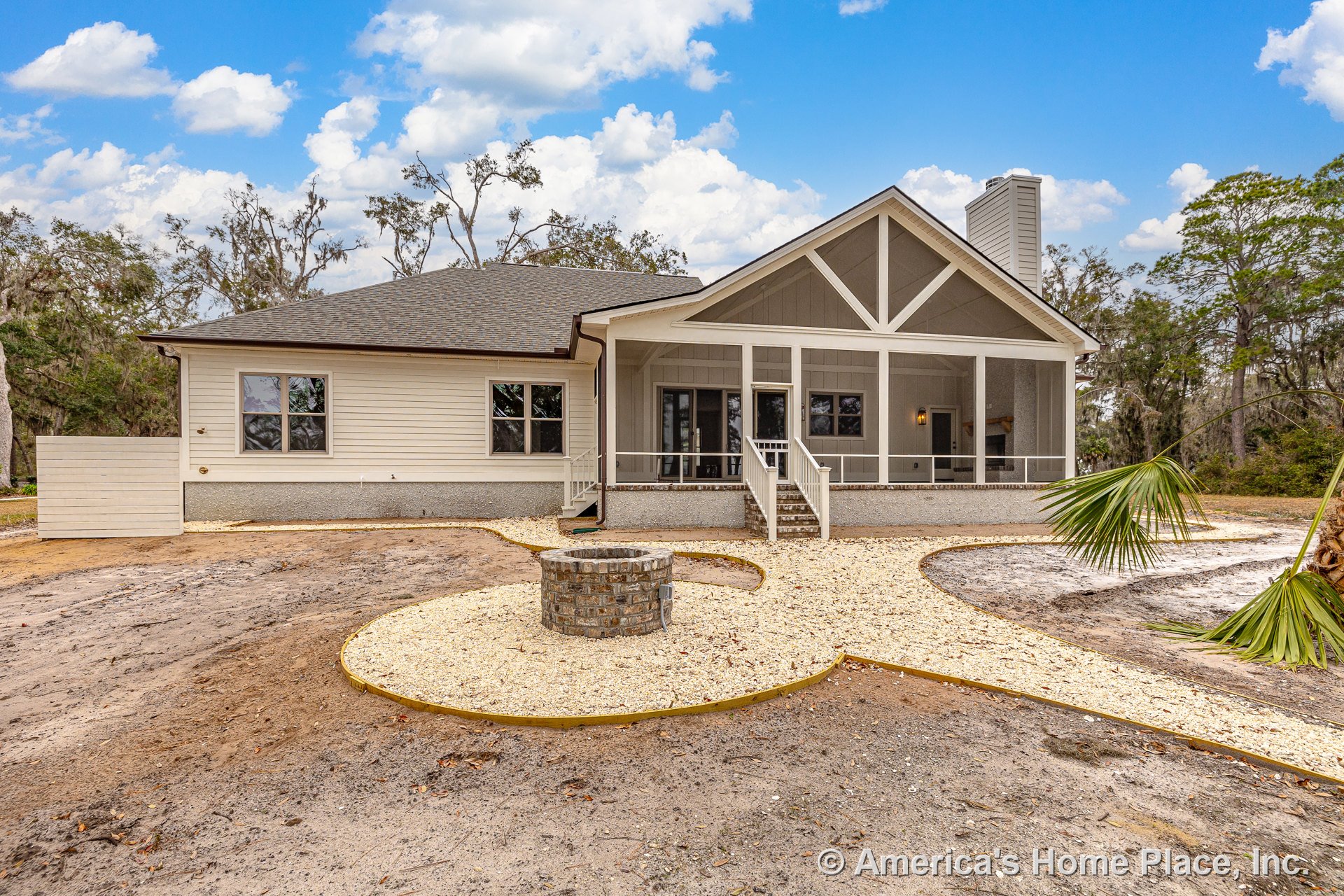 Large screened porch with exposed truss beams and railing, double front doors, horizontal siding, architectural shingle roof, brick fire pit in landscaped front yard, exterior