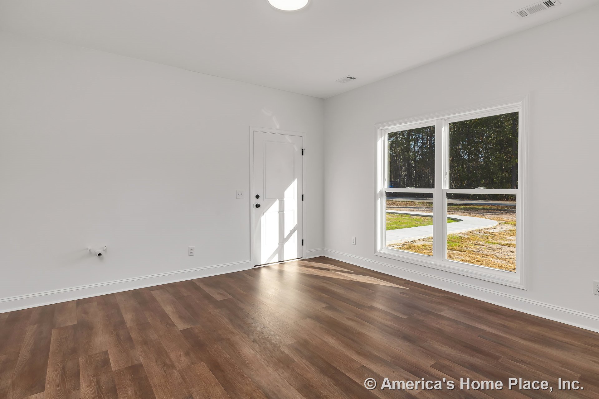Laundry or mudroom with double window framed in white trim, wood-look vinyl plank flooring, white door with black hardware, wall-mounted laundry hookups, white baseboards, and