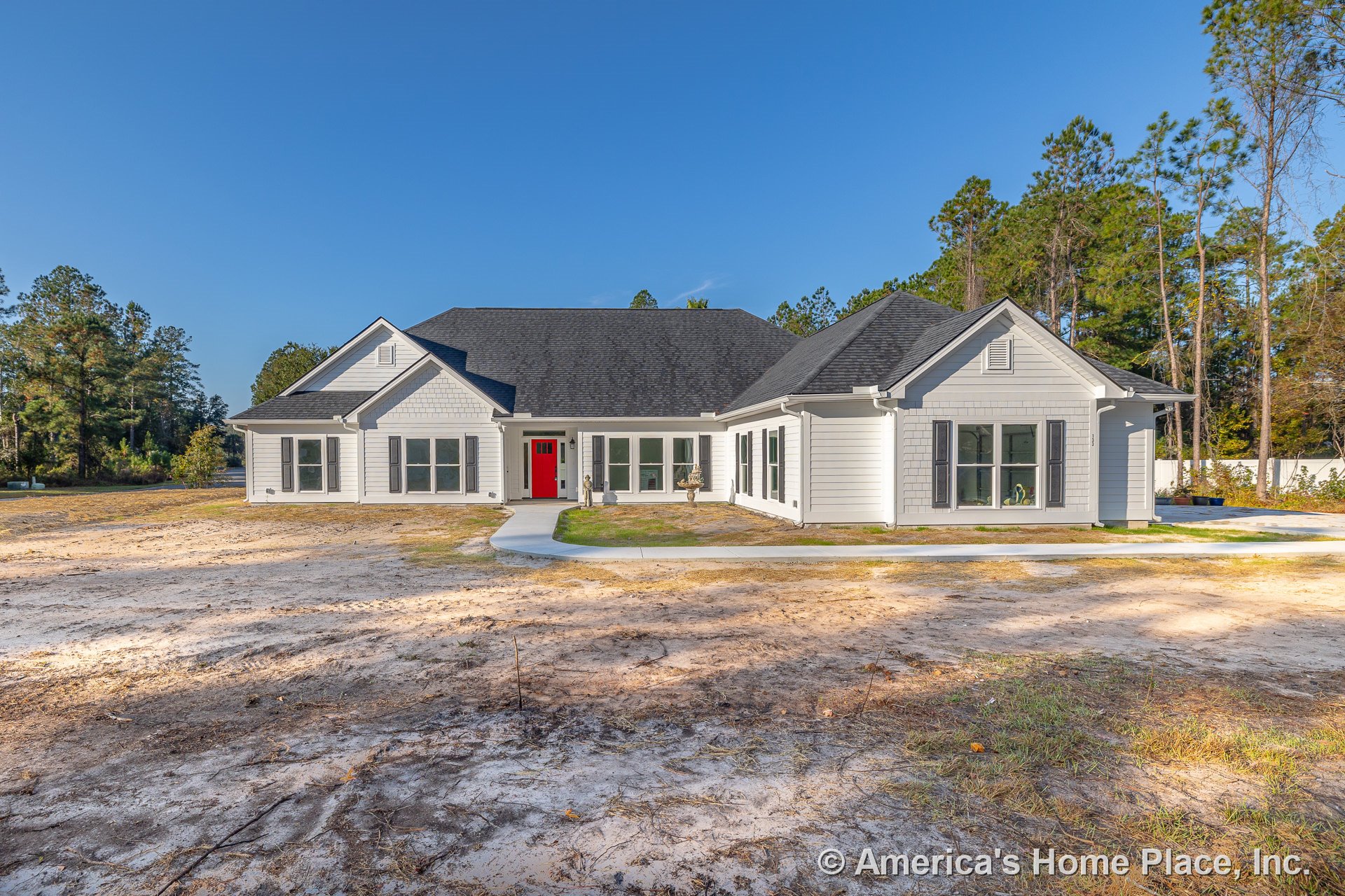 Light gray horizontal lap siding with white trim, black shutters, multiple large windows, prominent red front door on covered front porch, dark shingle roof with gabled rooflines.