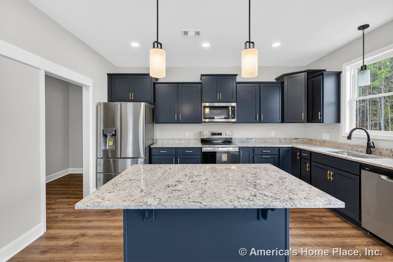 Navy cabinetry with gold hardware, granite countertops, large kitchen island, stainless steel appliances, pendant lighting fixtures, wood-look flooring, white trim, window
