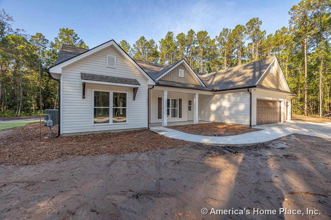 Covered front porch with white columns, double garage doors, large front windows with white trim, horizontal white siding, gable roof, and concrete driveway.